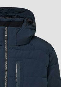 Granatowa pikowana kurtka z wysokim kołnierzem, przednim zamkiem błyskawicznym i zamykaną kieszenią na piersi. Teksturowana tkanina o gładkim wykończeniu.