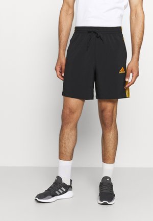 Schwarze sportliche Herren-Shorts mit einem Kordelzugbund, die auf den Seiten drei gelbe Streifen und ein orangefarbenes Logo auf der Vorderseite haben.