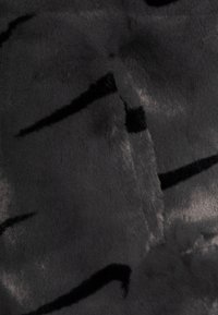 Měkký černý umělý kožich se hladkým povrchem, který má jemný vzor tmavších pruhů vytvářející kontrast na svém povrchu.