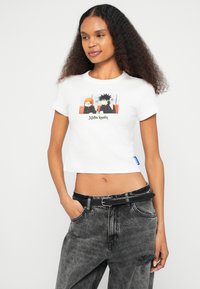 Λευκό κοντό μπλουζάκι με γραφικό εκτύπωσης κινουμένων σχεδίων. Κατασκευασμένο από βαμβάκι, με κοντά μανίκια και στρογγυλή λαιμόκοψη.