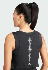 Camiseta atlética negra sin mangas con un corte ajustado, que presenta un patrón gráfico blanco en la espalda y un logo de Adidas en el dobladillo.