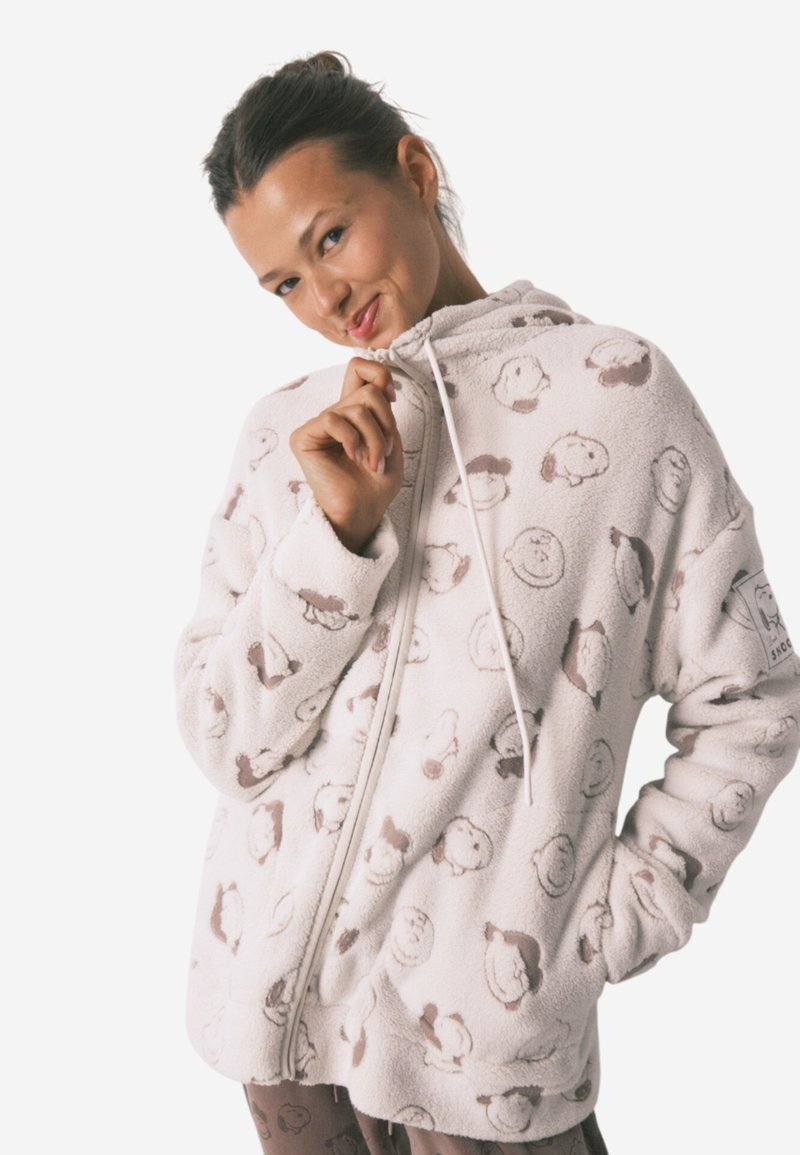 Fleece zip-up hoodie i lys creme med brun tegneserie dyreprint; har en snøre i hætten og to sidelommer for ekstra komfort.