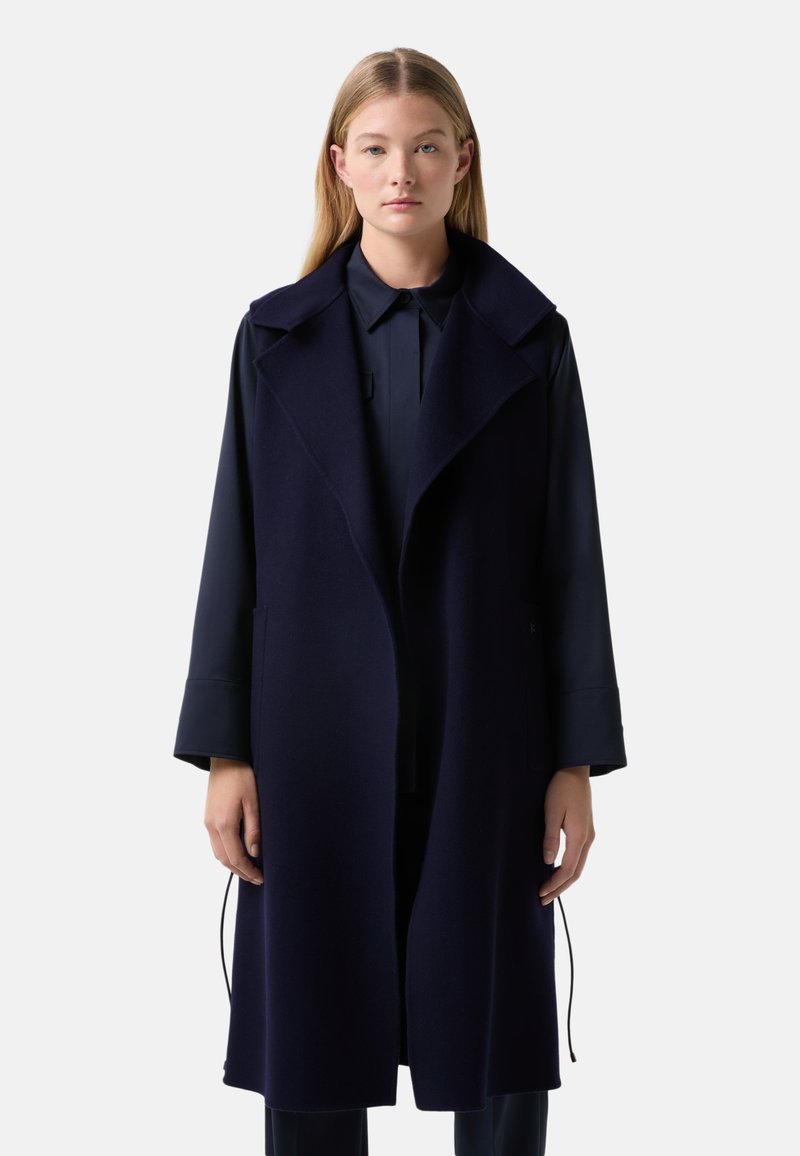 Navy blue wool long coat with a wide collar, open front, and side pockets. The sleeves are wide and the texture appears soft.