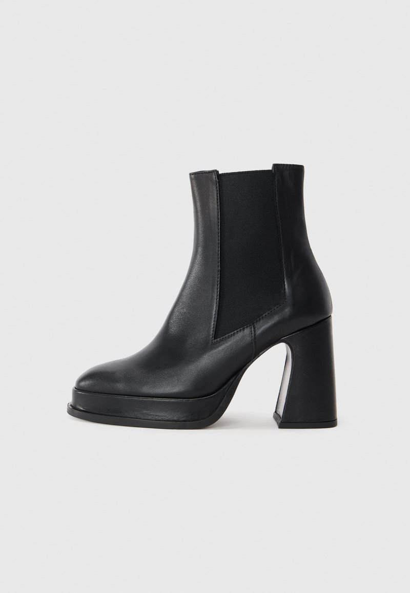 Botas de cuero negras hasta el tobillo con paneles laterales elásticos, puntera redonda y un alto tacón de bloque. Textura suave con un brillo sutil.
