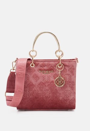 Różowa, teksturowana welurowa torebka z złotymi górnymi uchwytami, odpinanym szerokim paskiem na ramię oraz złotym logo i zawieszką River Island London.