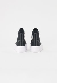 Sneaker alte in tela nera con suole in gomma bianche, caratterizzate da un logo circolare sulla caviglia e dettagli di cuciture bianche.