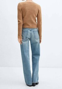 Brązowy sweter dzianinowy w połączeniu z jasnoniebieskimi spodniami z wysokim stanem i prostymi nogawkami. Sweter ma prosty dekolt i długie rękawy.