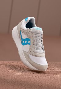 Grey and white sneaker with blue accents, featuring a mesh upper, suede overlays, and thick rubber sole. Laces are light grey.