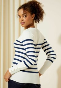 Maglione a strisce blu navy e bianco con maniche lunghe, polsini a coste e scollo rotondo; presenta dettagli con bottoni sulle maniche.