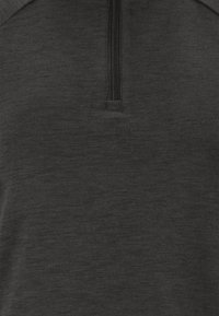 Schwarzer Pullover mit halbem Reißverschluss am Kragen, aus strukturiertem Stoff mit weicher Optik und dezentem Muster.