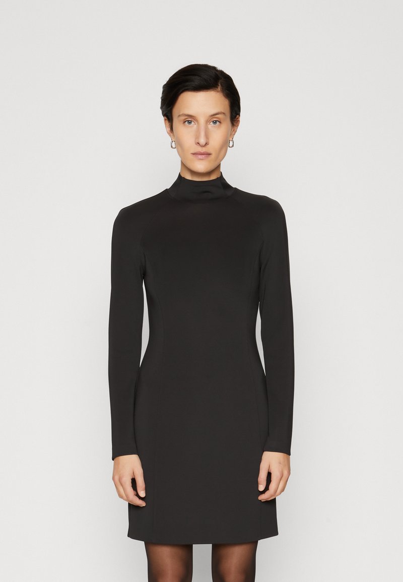 Robe noire à manches longues avec un col haut, faite d'un tissu lisse, présentant une silhouette ajustée et un design minimaliste.