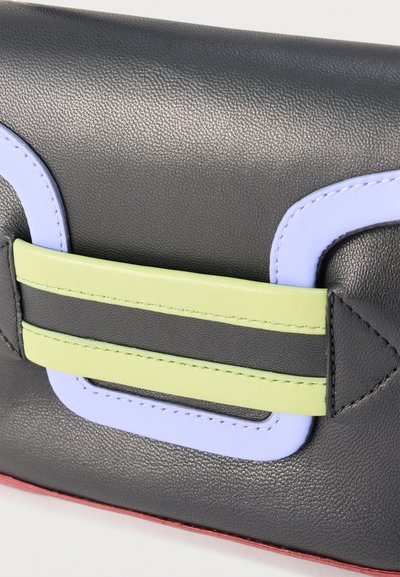 Κοντινό πλάνο μαύρης δερμάτινης τσάντας με παστέλ πράσινο λουράκι και λιλά γεωμετρική διακόσμηση, που δείχνει λεπτομερή ραφή και υφή.
