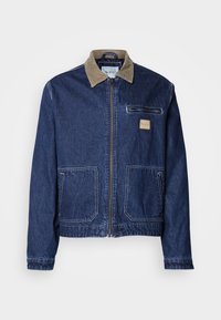 Jachetă din denim de culoare albastru închis, cu guler din catifea, închidere cu fermoar în față, două buzunare mari și un buzunar pe piept. Prezintă un patch cu logo pe piept.