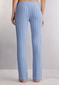 Blauwe gestreepte pyjamabroek met een zachte textuur, elastische tailleband en opgerolde boorden. Verticale witte strepen contrasteren met de blauwe stof.