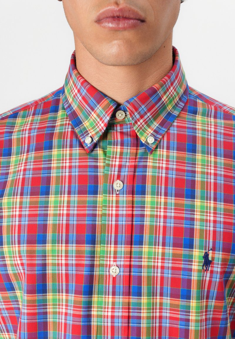 Kolorowa koszula w kratę z mieszanką czerwonego, niebieskiego, zielonego i żółtego. Zawiera kołnierzyk zapinany na guziki oraz małe logo na piersi.