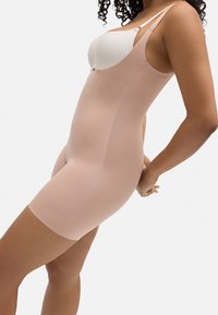 Body moldeador nude con tirantes ajustables, textura suave, longitud a mitad de muslo y diseño sin costuras para un ajuste invisible bajo la ropa.
