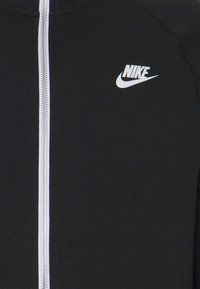 Černá mikina na zip s centrálním stříbrným zipem a bílým logem Nike na pravé straně hrudi.