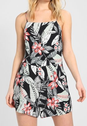 Robe courte noire à motifs floraux, ornée de motifs de feuilles rouges et vertes, avec des bretelles fines et un corsage ajusté, reflétant un bas décontracté.