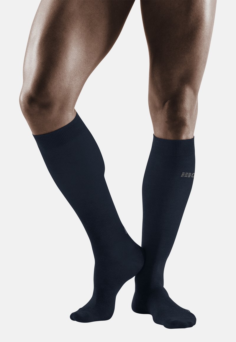 Marinefarbene knielange Kompressionssocken, glatte Textur, gerippter oberer Bund, minimale Markenkennzeichnung in der Nähe des Knöchels. Entworfen für Unterstützung.