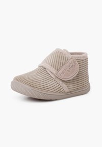 Beige corduroy pantoffel met een klittenbandsluiting, een gestructureerd oppervlak, een afgeronde vorm en een rubberen zool; heeft lichte stitching en een zachte voering.