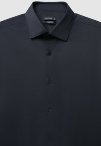 Schwarzes Slim-Fit-Hemd mit glatter Textur, Knopfleiste und klassischem Kragen. Ausgestattet mit bügelleichtem Material für geringen Pflegeaufwand. Größe L.