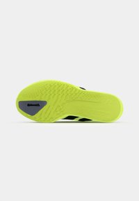 Black athletic shoe outsole with a bright neon yellow surface, featuring textured grip patterns and a grey Continental logo detail.