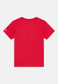 Rød bomulds T-shirt med rund hals, korte ærmer og et logo trykt på venstre ærme. Glat tekstur med ensfarvet design.