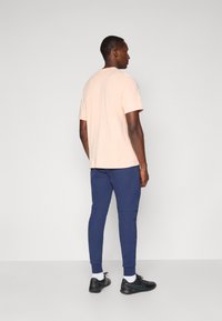 Light pink short-sleeved t-shirt, navy joggers, black athletic shoes with white socks. Simple design, soft texture, straight cut.