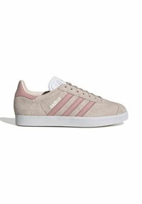 Beige zamšas sneakers ar rozā ādas akcentiem, kurām ir trīs baltas svītras, teksturēta balta gumijas zole un klasiska saišu dizains.