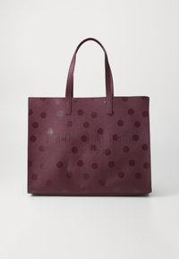 Bordeaux kleurige tote bag met een patroon, voorzien van grote tonale stippen en de gegraveerde tekst "TED BAKER LONDON" aan de voorkant. Duurzaam materiaal en dubbele handvatten.