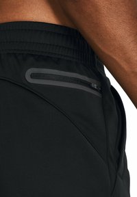 Zwarte sportshorts met een gestructureerde afwerking, voorzien van een ritszak aan de zijkant en een elastische tailleband voor een veilige pasvorm.
