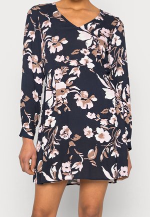 Robe fleurie bleu marine avec des fleurs roses et beiges. Manches longues, col en V et silhouette fluide. Tissu doux avec une texture légère.