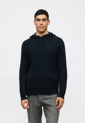 Donker marineblauwe hoodie van zachte stof, met een kangoeroezak, een capuchon met trekkoord en ribgebreide manchetten en onderkant, gedragen met een grijze jeans.