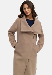 Beige Wollmischung Mantel mit übergroßem Kragen, Frontreißverschluss, seitlichen Taschen und glatter Textur. Taillierte Passform mit klaren Linien.