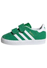 Green suede sneaker with white textile stripes and accents, Velcro closures, and a textured white rubber sole. Gold logo detail on side.