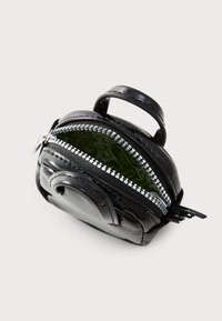 Small shiny black zipper pouch with a top handle and partially open silver zipper showing patterned green interior lining.