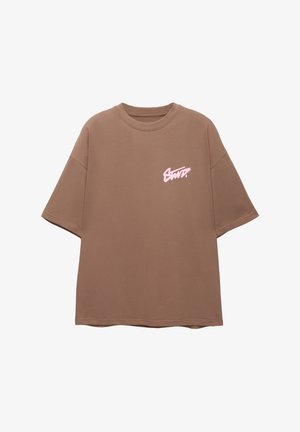 Brown oversized t-shirt made of soft cotton with a round neck and short sleeves. Features a pink logo on the left chest area.