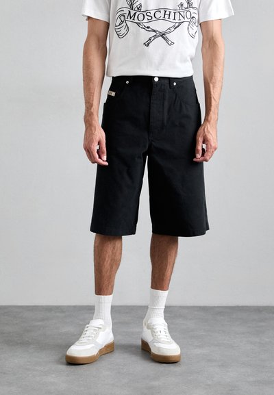 Zwarte katoenen shorts met een rechte snit en omslagrand, gecombineerd met een wit graphic t-shirt en witte sneakers met rubberen zolen.