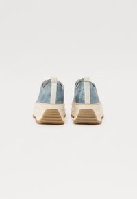 Kék fémes slip-on cipők vastag fehér középtalppal és taupe gumitalppal. Hátul hurok segíti a könnyű felhúzást.