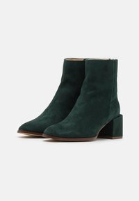 Botas de tobillo de ante verde con tacón cuadrado, diseño de punta afilada, textura suave y cremallera lateral para facilitar su uso.