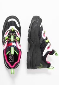 Sneakers neri in tessuto con accenti rosa, pannelli in rete e lacci verdi. Presentano una toppa con logo bianco e una suola in gomma testurizzata per una buona aderenza.
