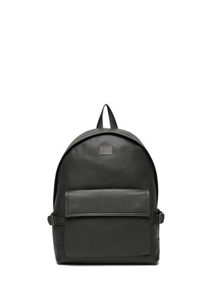 Černý kožený batoh s přední kapsou na zip, horním držadlem a nastavitelnými bočními popruhy na bílém pozadí.