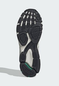 Sport shoe sole featuring a black rubber design with textured patterns and green accents, providing traction and stability.