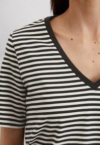 Gestreiftes Kurzarmtop in Schwarz und Weiß, mit einem V-Ausschnitt und einer weichen Baumwollstruktur in normaler Passform.