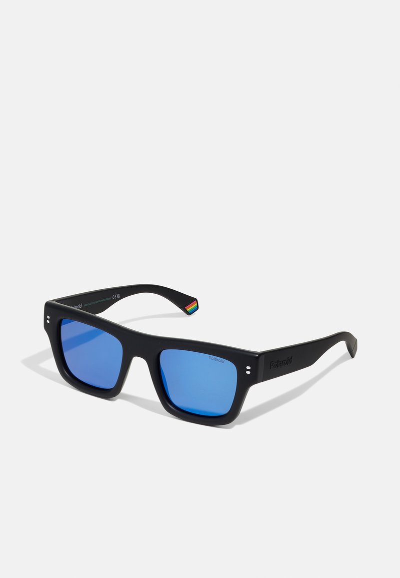 Occhiali da sole in plastica nera con lenti blu, montatura quadrata e piccolo dettaglio arcobaleno sulla tempia. Presentano il marchio Polaroid sulla lente.