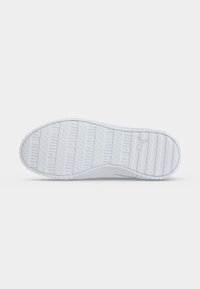 Semelle blanche de chaussure avec motifs texturés antidérapants et logo Puma près du talon, présentée sur un fond blanc uni.