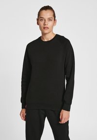 Zwarte sweatshirt van zachte stof, met een ronde hals, raglanmouwen en ribgebreide manchetten en zoom. Minimalistisch ontwerp zonder zichtbare patronen.
