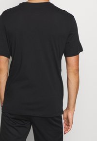 Sort kortærmet T-shirt lavet af bomuld, med en klassisk rund hals og glat tekstur, med et ensfarvet design og uden synlige logoer.