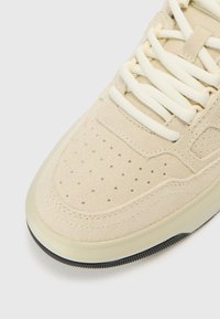 Beežid seemisnahast tossud ümmarguse varbaga, puuritud pealsega, kreemika värvi paeltega, tekstuurse külgpaneeli ja läbipaistva kummist tallaga.