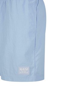 Shorts bleu clair en tissu texturé, dotés d'une taille élastique et d'une étiquette blanche à l'ourlet avec les détails de la marque.